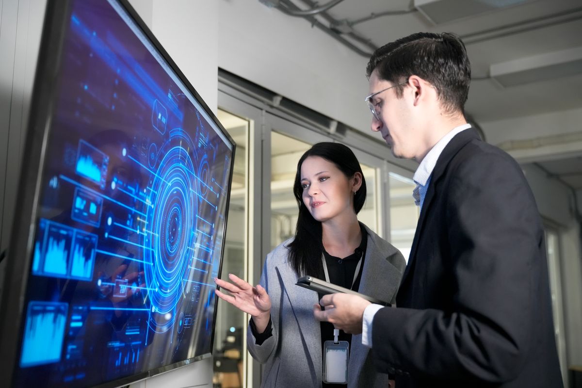 Two professionals discussing data on a large interactive display during a security solution consultation